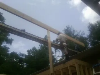 Carpenter setting a ridge beam over a new addition frame — Ice Dam Removal by Roofing Brothers in King