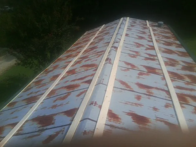 Rusted metal roof panels with new wood purlins before replacement — Storm Damage Roof Repair in King by Roofing Brothers