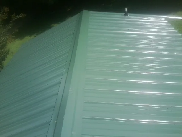 New green metal panels meeting at the ridge of a roof — Flat Roof Repair work by our crew in King
