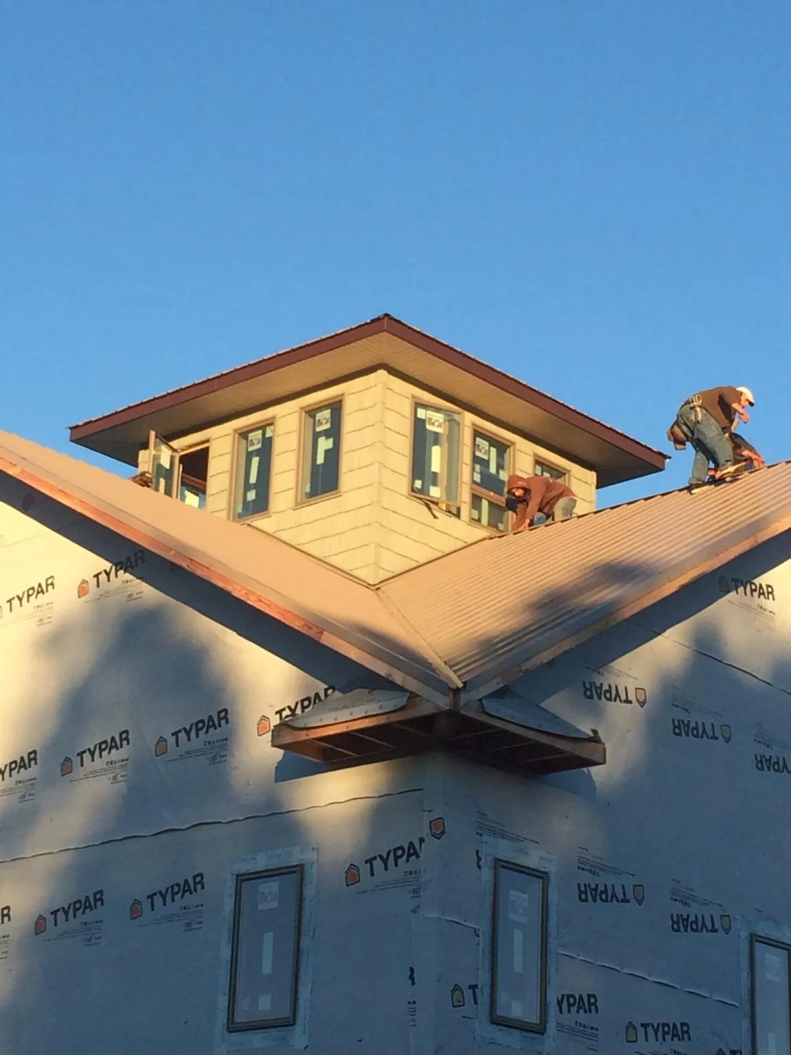 Roofers working around a rooftop cupola on a new metal roof at sunset — Roof Waterproofing in King by Roofing Brothers